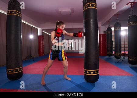 Kickboxer-Mädchen, die mit der schweren Tasche, den Schlägen und Tritten arbeiten Stockfoto