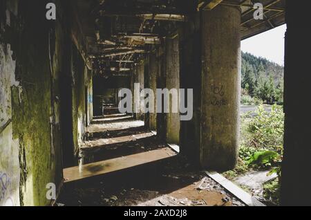 Sete Cidades, Azoren, Portugal - 12. Januar 2020: Verlassenes Hotelgebäude auf dem berühmten Aussichtspunkt auf den portugiesischen Inseln. Gebäude aus leerem Beton. Schatten und Sonnenlicht. Stockfoto