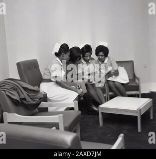 1960er Jahre, historisch, vier Krankenschwestern sitzen zusammen in einem Gemeinschaftsraum und schauen durch eine medizinische Broschüre, Brook General Hospital, South London, England, Großbritannien. Stockfoto