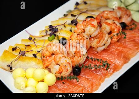 Verschiedene Garnelen, Forellen und ölige Fische mit Ölkugeln und schwarzen Oliven Stockfoto