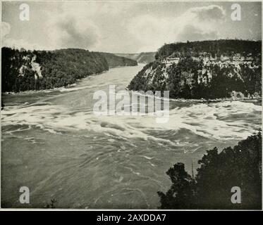 Ein Souvenir der Niagarafälle mit Blick Auf Die Niagarafälle Und ihre Umgebung. A nearor View u[ tliu Jjli;ul Arch Biiil^t: F Il.: (.1slinvitii; ilie Village &lt;.f Susiension Uiid;;e on the Aimi Arii-r; -.1:1 r.idu. CRRMD TRUNK RRILVRT STAHLBOGEN DRIDCc 111 (1 Tinnk Railway, mit Fioiii das kanadische Ende der Michigan Central Steel Cantilever Bridge und CAN Side. Diese Ansicht zeigt auch die Linie der Niagara-Gorge-Route, in der Nähe des Tlie Waters cdf^e auf der. Der WHIRLPOOL Unterhalb von [HE Knver Rapids tbe schlucht l.ilces an abrupte turu nach Osten, funning a Great Basin of s Stockfoto