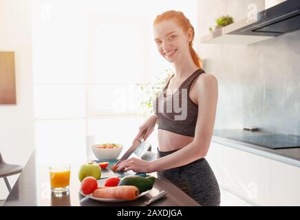 Sportliches Mädchen mit Turnhallenkleidung isst in der Küche Obst Stockfoto