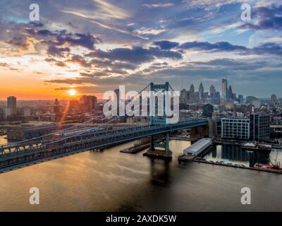 Philadelphia mit der Ben Franklin Brücke bei Sonnenuntergang, Silhouette der modernen Skyline gegen den dramatischen Himmel Stockfoto