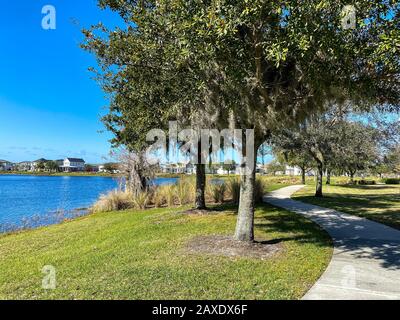 Orlando, FL/USA-2/10/20: Ein geschwungener Gehweg neben einem See, der ein Fußweg in Hinterhäusern im Laureate Park Lake Nona an Orlando, Florida neigh ist Stockfoto