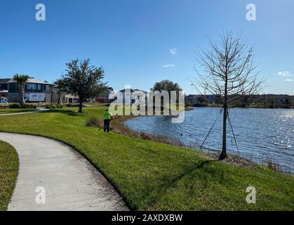 Orlando, FL/USA-2/10/20: Ein geschwungener Gehweg neben einem See, der ein Fußweg in Hinterhäusern im Laureate Park Lake Nona an Orlando, Florida neigh ist Stockfoto