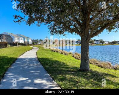 Orlando, FL/USA-2/10/20: Ein geschwungener Gehweg neben einem See, der ein Fußweg in Hinterhäusern im Laureate Park Lake Nona an Orlando, Florida neigh ist Stockfoto