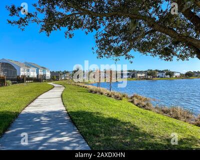 Orlando, FL/USA-2/10/20: Ein geschwungener Gehweg neben einem See, der ein Fußweg in Hinterhäusern im Laureate Park Lake Nona an Orlando, Florida neigh ist Stockfoto