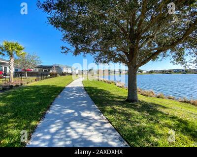 Orlando, FL/USA-2/10/20: Ein geschwungener Gehweg neben einem See, der ein Fußweg in Hinterhäusern im Laureate Park Lake Nona an Orlando, Florida neigh ist Stockfoto