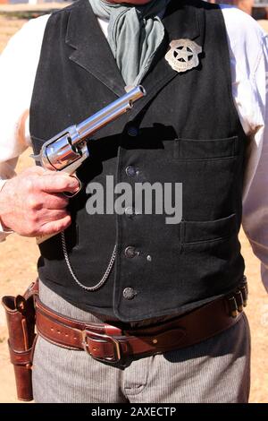 Nahaufnahme eines US-amerikanischen Marschall-Stars und des Colt Peacemaker Revolvers, der stolz vom Reenactor bei einer Veranstaltung in Tucson AZ gezeigt wurde Stockfoto