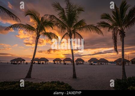 Strohhütten an einem Strand in Florida mit wunderschönem Sonnenuntergang, paradiesischer Ausflug Stockfoto