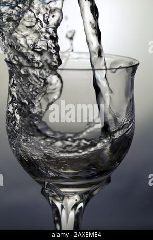 Wasser spritzt in einem feinen Kristallglas auf Stockfoto