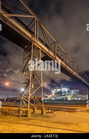 Nachtaufnahme mit beleuchteten petrochemischen Produktion und massive Pipeline Überführung, Antwerpen, Belgien. Stockfoto