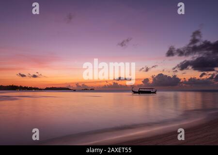 Bei Sonnenuntergang auf den Malediven segelt ein Dhoniboot über das Meer Stockfoto