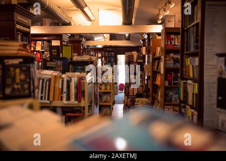 Unorganisiertes Buchladen mit Stapeln von Büchern in den Regalen Stockfoto