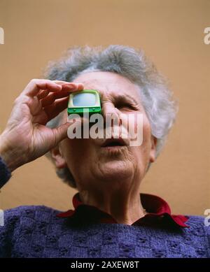 Niedriger Blickwinkel einer Seniorin, die durch einen TV-Zuschauer blickt, Deutschland Stockfoto