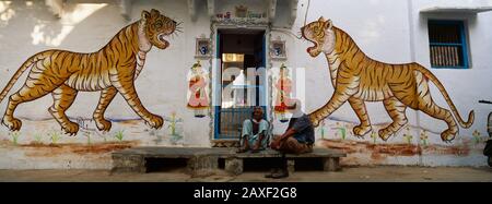 Zwei reife Männer sitzen vor einer Tür eines Gebäudes, Udaipur, Rajasthan, Indien Stockfoto