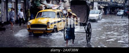 Autos und eine Rikscha auf der Straße, Kalkutta, Westbengalen, Indien Stockfoto