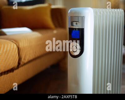 Nahaufnahme auf modernem Boden weißer Elektro-Ölkühler mit Thermostat zu Hause im sonnigen Wintertag. Stockfoto