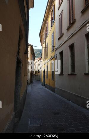 Blick entlang der engen und verwinkenden Via Giuseppe Rovelli, Häuser, Sonnenlicht auf einen Palazzo, Nachmittag in der Altstadt, Como, Lombardei Italien, Stockfoto