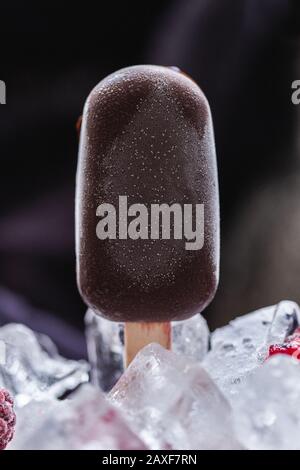 Vertikale Aufnahme von hausgemachten veganen Eiscreme mit Schokolade und bedeckt Umgeben von Eiswürfeln Stockfoto