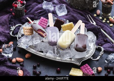 Schöne Aufnahme von hausgemachtem veganem Eis und Schokoladenriegel Auf Eiswürfeln in einer Metallplatte Stockfoto