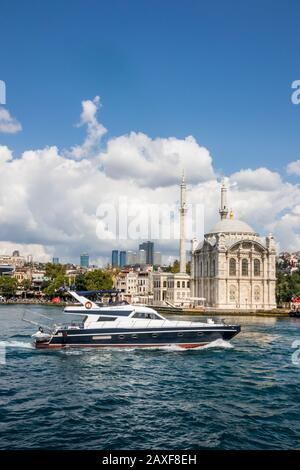 Istanbul, Türkei - 30. August 2019: Ein Motorboot fährt mit der Martyr-Brücke am 15. Juli vorbei an der Ortaköy-Moschee. Stockfoto