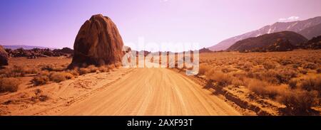 Die schmutzige Straße führt durch eine aride Landschaft, die kalifornische Sierra Nevada, Kalifornien, USA Stockfoto