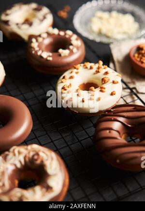 Vertikale Aufnahme von leckeren Donuts in der weißen und bedeckt Braune Schokoladenglasur auf einem Küchentisch Stockfoto