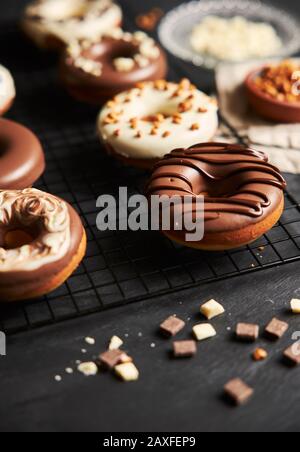 Vertikale Aufnahme von köstlichen Donuts in der weißen und bedeckt Braune Glasur und Schokoladenstücke Stockfoto