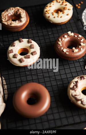 Vertikale Schuss von köstlichen Donuts in der Schokolade Glasur bedeckt Auf einem schwarzen Tisch Stockfoto