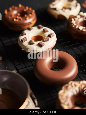 Vertikale Schuss von köstlichen Donuts in Glasur und Schokolade bedeckt Stücke auf einem schwarzen Tisch Stockfoto