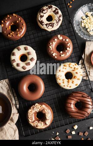 Vertikale Schuss von köstlichen Donuts in der Schokolade Glasur bedeckt Auf einem schwarzen Küchentisch Stockfoto