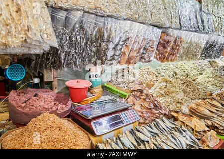 Nahaufnahme von Haufen getrockneter, gesalzter kleiner Fische in Bambuskörben und plastig Tüten und Garnelenpaste zum Verkauf auf einem Markt in Iloilo, Philippinen, Asien Stockfoto