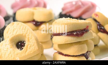 Schokoladenkuchen mit Himbeer-Buttercreme-Aufschäumen und herzförmigen Plätzchen schließen sich auf weißem Hintergrund, Draufsicht. Stockfoto