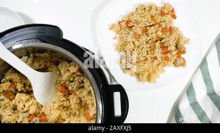 Reis, Gemüse und Fleisch in einem Topf und auf einem Teller. Kochen von Reis mit Fleisch und Gemüse (oder Reis Pilaf) im Druck Multi-Herd Schritt für Schritt, oben Stockfoto