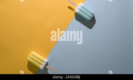 Draufsicht über Limette und blaue Himbeere Aroma Popsicles und Kopierraum, Sommer Minimalkonzept auf flachem Lay gelb und blauem Hintergrund Stockfoto