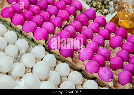 Weiße Eier neben rot gefärbten, gedämpften, salzigen Eiern und Wachteleiern, die auf einem nassen Markt in Iloilo, Philippinen, Asien zum Verkauf angeboten werden. Diagonale Anzeige. Stockfoto