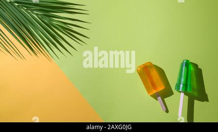 Draufsicht auf Limetten und Orangenpopskel, Palmblatt- und Kopierraum, im Sommer minimales Konzept auf flachem, gelbem und grünem Hintergrund Stockfoto