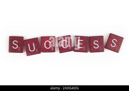 Das Wort Erfolg hat in einer ungleichen Anordnung von Spielbuchstaben-Kacheln geschrieben. Stockfoto