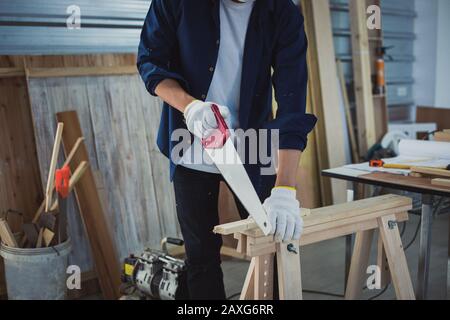 Asian man Carpenter arbeitet mit technischem Zeichnen oder Baupapier, das auf einer Werkstatt mit Zimmermannswerkzeugen und Holz zu Hause liegt Stockfoto