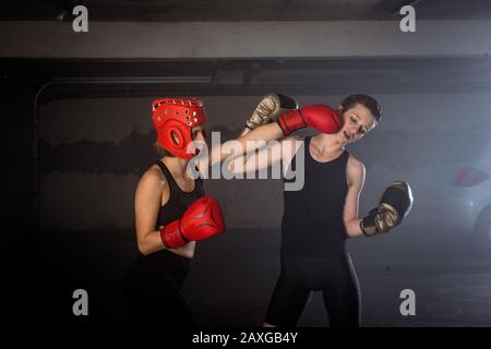 Zwei professionelle Boxerinnen stanzen sich im aggressiven Garagenboxkampf Stockfoto