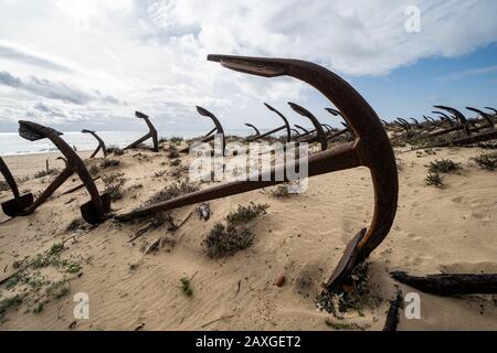 Verrosteter alter Anker am Strand am Friedhof von Anchor Cemetary am Strand Praia do Barril in Tavira, Algarve, Portugal Stockfoto