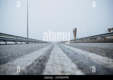 Die Trennlinie auf der Straße ist weiß, die Ansicht von unten auf der Straße, die asphaltiert ist. Straßenmarkierungen auf Asphalt auf der Straße. Stockfoto