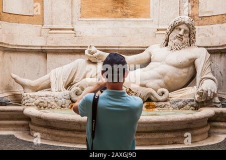 Ein Tourist findet einen Springbrunnen mit Marforio, Flussgott, Kapitolinmuseum, Rom, Italien. Stockfoto