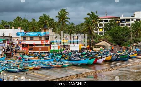Wunderschönes Küstenstranddorf in Indien, wo Bunte Fischkanus außerhalb der Saison vor dem Meer verankert sind und die Wettervorhersage sehr rau ist. Stockfoto
