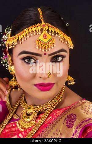 Porträt einer jungen und schönen indianischen bengalischen Brunette-Frau in Rot und Weiß traditionelle ethnische Sari Stockfoto