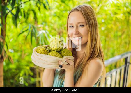 Cherimoya in einer wiederverwendbaren Tasche in weiblichen Händen. Null-Abfall-Konzept, plastikfreies Konzept. Gesunde, saubere Ernährung und Entgiftung. Sommerfrüchte Stockfoto