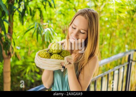 Cherimoya in einer wiederverwendbaren Tasche in weiblichen Händen. Null-Abfall-Konzept, plastikfreies Konzept. Gesunde, saubere Ernährung und Entgiftung. Sommerfrüchte Stockfoto