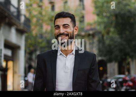 Gutaussehender arabischer Kerl lächelt. Erfolgreicher Mann, der auf der Straße spazieren ging Stockfoto