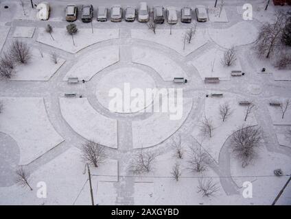 Blick von oben auf den Hof des Wohnhauses nach Schneefall mit schneebedeckten Autos. Stockfoto